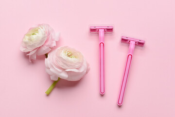 Safety razors and flowers on pink background