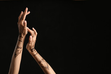 Female hands with henna tattoo on dark background