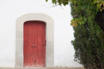Fototapeta na wymiar Puerta roja arboles y pared blanca vintage retro