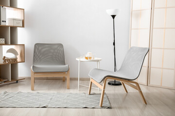 Stylish modern armchairs in interior of light living room