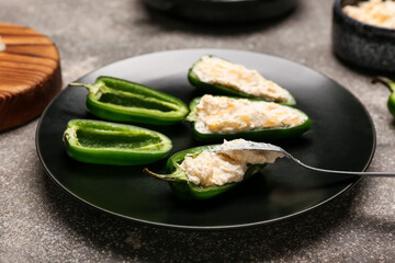 Plate with uncooked jalapeno poppers on grey background, closeup