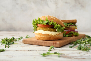 Wooden board with tasty vegetarian burgers on table