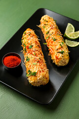 Plate with tasty Elote Mexican Street Corn on green wooden background