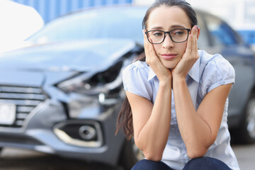 Portrait of a sad woman on background of broken car closeup