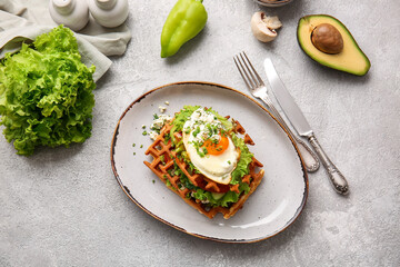 Tasty Belgian waffles with egg and vegetables in plate on light background
