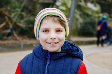 Outdoor portrait of little kid boy in spring or autumn colorful clothes. Happy boy having fun in a...