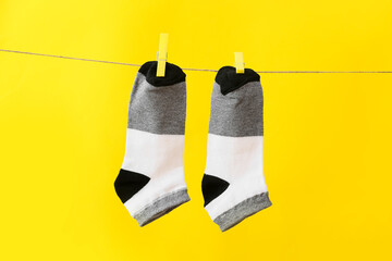 Pair of socks hanging on rope against yellow background
