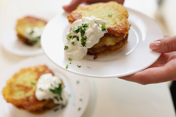 Potato pancakes with sour cream and herbs on plate