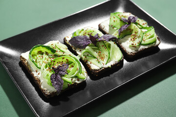 Plate with tasty vegetarian bruschettas on green background, closeup