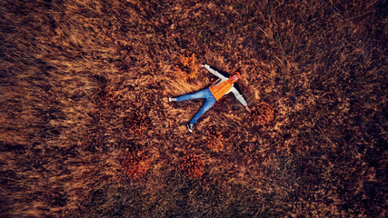Aerial drone view of a man lying in autumn colored grass.