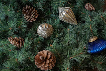 Different christmas decorations and pine cones on green branches background and copy space.