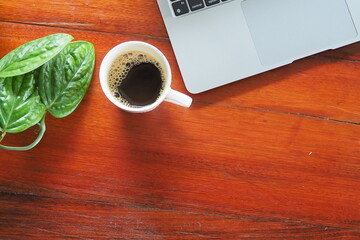 Coffee and laptop on wooden desk.
