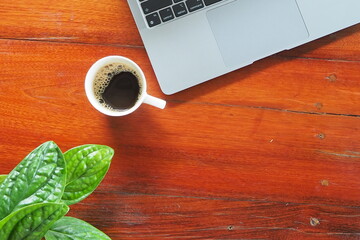 Coffee and laptop on wooden desk.