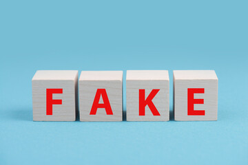 The word fake is standing in red color on wooden cubes, blue background