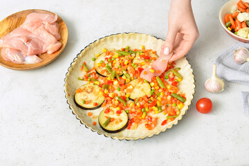 Woman preparing chicken pot pie with vegetables on white background