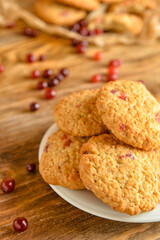 Plate with tasty cranberry cookies on wooden background, closeup