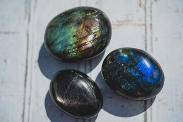 labradorite and hypersthene palm stones on white wood