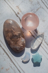 flower agate, rose quartz, quartz, chalcedony, amazonite palm stones, sphere, moon, and star on white wood
