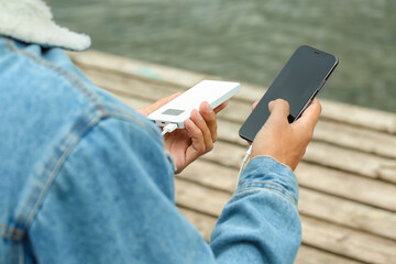 Young man with phone and power bank near river, closeup