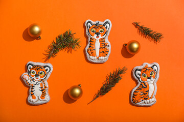 Cute cookies in shape of tiger and New Year decor on color background