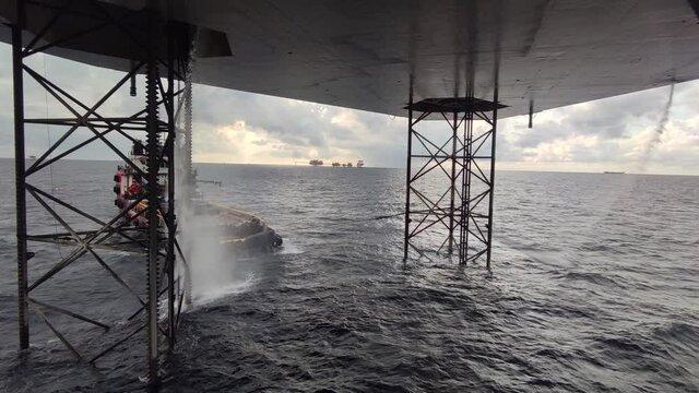 View Underneath Jack Up Drilling Rig In The Ocean with a supply boat and a central processing platform
