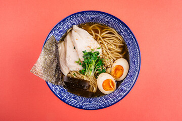 Top view on shio ramen noodle thick soup with chicken and eggs on pink background