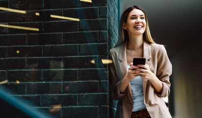 Portrait of successful woman with mobile in urban background. Business technology device concept