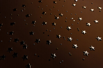 Gold sparkles and stars on a dark festive background, confetti with glitter top view. An evening card with luxury elements.