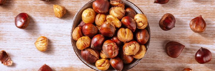 Baked chestnuts panorama, autumn food panoramic banner, overhead flat lay shot on a rustic wooden background