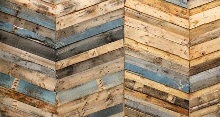 Highly unique abstract geometric patterns made from recycled cut timber palettes arranged in diagonal stripes. Multi colored textural upcycled planks of wooden parquetry in a herringbone composition.