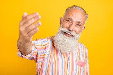 Photo of hospitable retired man show invite gesture wear striped shirt isolated yellow color background
