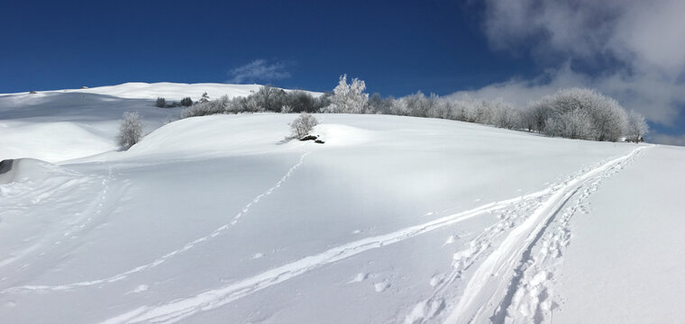 beautidul snowy mountain with tracks under blue sky