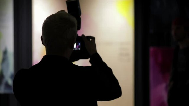 Reportage photographer takes pictures of people in an art gallery