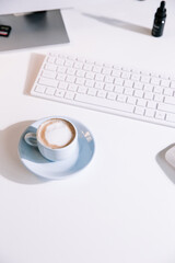 Fototapeta premium Light blue coffee cup flat lay with computer and table, minimalism and mood
