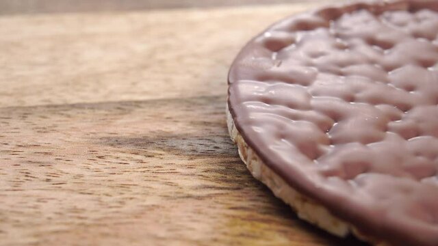 Crispy chocolate rice cake on a rustic wooden surface. Macro. Dolly shot. Diet healthy food concept