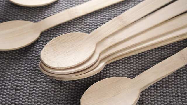 Organic biodegradable bamboo wooden spoon set falling on a textured natural burlap mat. Close up. Slow motion. Recycling eco-friendly concept