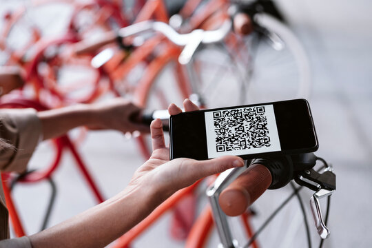 Businesswoman unlocking bicycle through smart phone at parking station