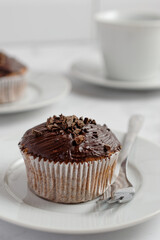 Close up of a chocolate muffin on a white plate