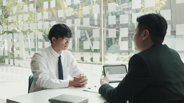 Male manager is talking or explaining about having to dismiss the employee while being handed out a resignation envelope to the employee.