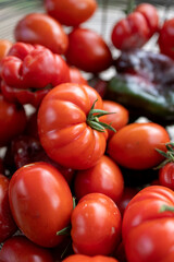 Close up shot of an iron basket filled with organic, fresh home grown tomatoes and some peppers, in all their natural imperfection. Farmer's market produce.