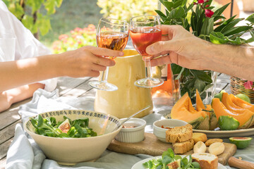 Family lunch on a sunny summer day. Wooden table with dishes on the street.
