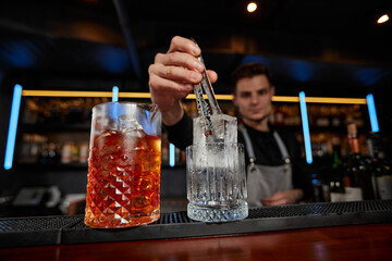 Barman puts the ice cubes into a glass