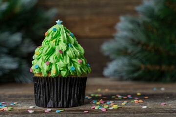 Christmas tree made of cupcake, cream decorated with confetti. New Year card. Christmas in a rustic style. copy space. Christmas background with fir tree and confetti. Blurred.