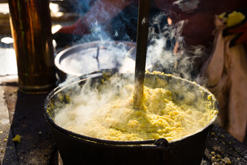 cauldron with polenta while cooking with wooden ladle