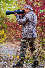 Naklejka premium professional photographer in camouflage clothes working in nature.