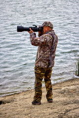 Naklejka premium professional photographer in camouflage clothes working in nature.