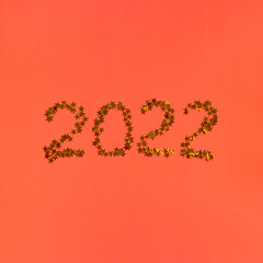 Numbers 2022 from gold stars glitter on red background. Christmas and New Year holiday cover