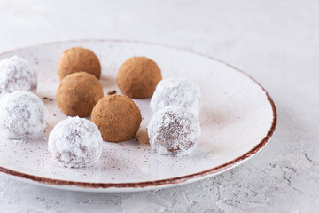 Fototapeta na wymiar Homemade truffles in cocoa powder and coconut milk powder on a plate.