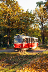 Fototapeta na wymiar Kyiv, Pushcha-voditsa, october 10, 2021. Red retro tram goes along the route through the autumn forest. Atumn landscape with tram.