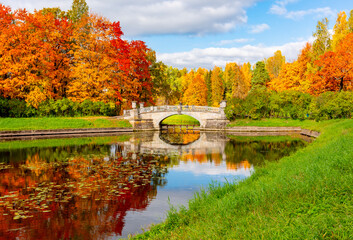 Fototapeta na wymiar Viskontyev bridge over Slavyanka river in autumn in Pavlovsky park, Pavlovsk, Saint Petersburg, Russia